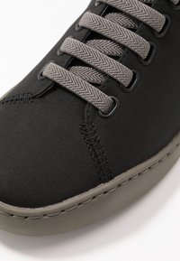 Czarny trampki na płótnie z szarymi sznurówkami, kontrastowymi przeszyciami i gumową podeszwą. Charakteryzuje się zaokrąglonym noskiem i teksturowaną powierzchnią dla lepszej przyczepności.