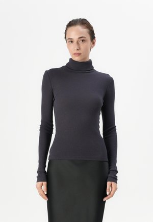 Dunkelgrauer, gerippter Rollkragenpullover mit langen Ärmeln, figurbetontem Design und glatter Textur. Kombiniert mit einem schwarzen Rock.