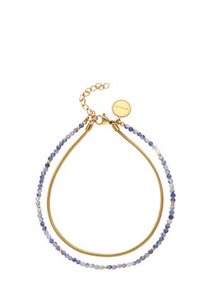 Pulsera de doble capa con pequeñas cuentas azules y blancas en una hebra y una cadena dorada en la otra, con un cierre dorado y una etiqueta redonda.