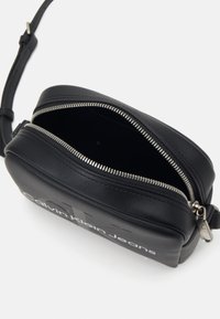 Borsa a tracolla in pelle nera con chiusura a zip, caratterizzata da logo impresso, accessori in argento, forma rettangolare e superficie liscia.