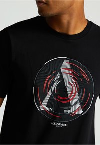 Čierne bavlnené tričko s okrúhlym grafickým dizajnom v bielej a červenej farbe so špirálovými vzormi a názvom značky "Alessandro Zavetti" na spodnej strane.