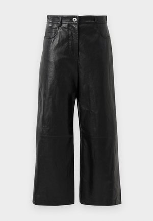 Calças largas de couro preto com uma textura suave, apresentando um fecho de correr e bolsos frontais. Design minimalista com um comprimento cortado.