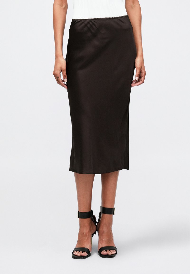 Gonna midi in satin marrone con una texture liscia, caratterizzata da una vita arricciata e una silhouette dritta, abbinata a scarpe con tacco nere a fascia.
