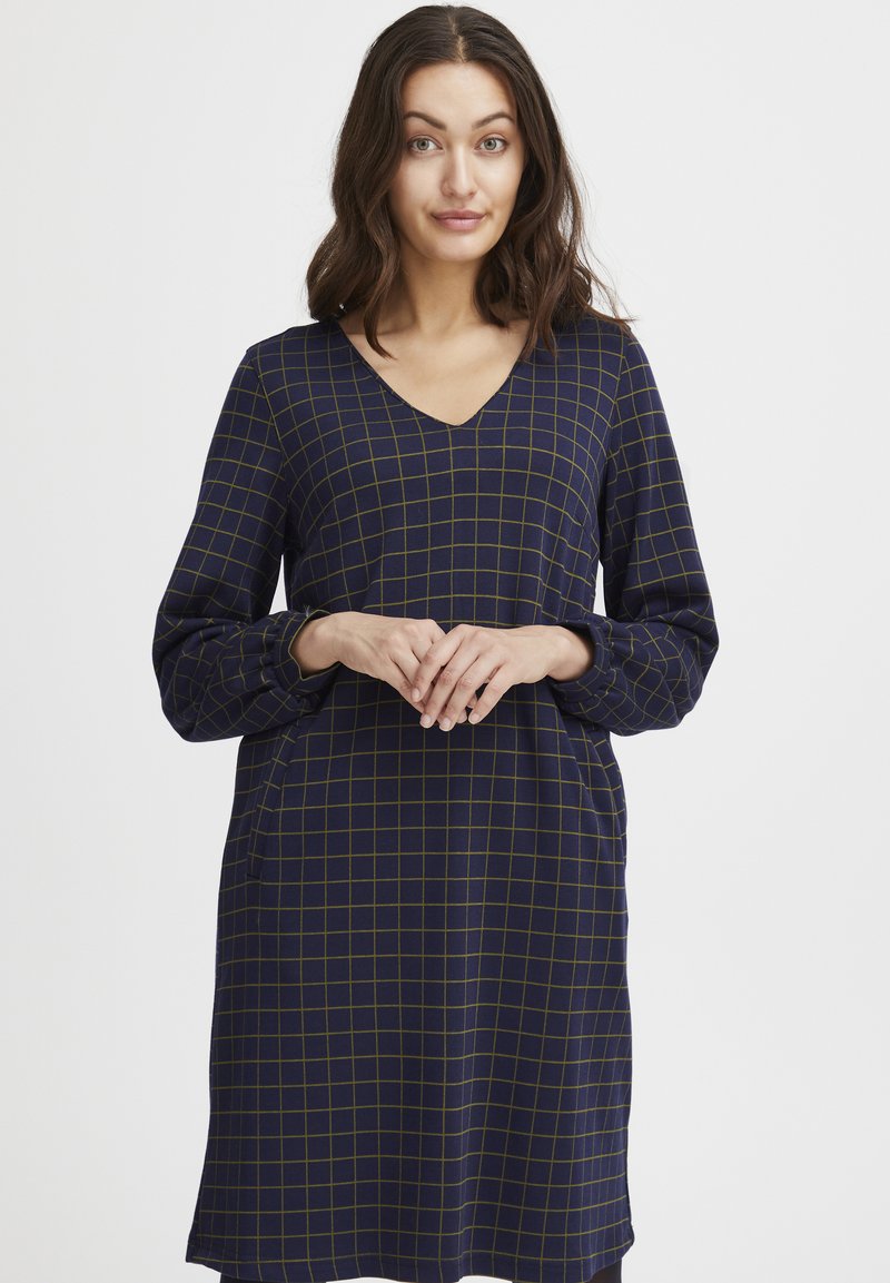 Navy Kleid mit V-Ausschnitt, langen Ärmeln und grünem Karomuster. Verfügt über Seitentaschen und eine lockere Passform für Komfort.