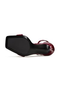 Sandale à talons hauts en cuir verni bordeaux avec une finition lisse, dotée de fines lanières et d'une semelle noire solide.