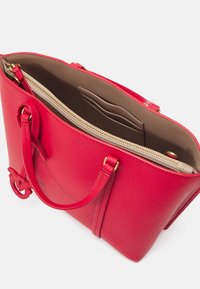 Sac à main en cuir rouge avec deux poignées, intérieur beige, poche zippée et emplacements pour cartes à l'intérieur, vu d'en haut.