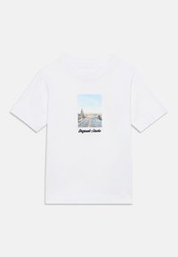 Λευκό βαμβακερό T-shirt με ορθογώνιο σχέδιο που απεικονίζει μια σκηνή δρόμου με γαλάζιο ουρανό και δέντρα, με την επιγραφή «Originals Studio» σε μαύρο κείμενο.