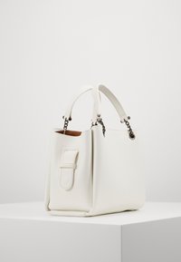 Vit läderhandväska med texturerad yta, dubbla handtag och en sidospänne detalj. Kompakt rektangulär form med accentdetaljer i silver.