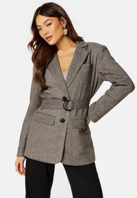 Blazer a motivo pied-de-poule in marrone e grigio, con cintura, due tasche frontali, rever a punta e chiusura con bottoni.