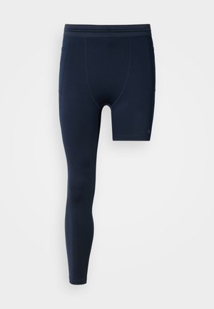 Tengerészkék sportlegging, testhez simuló fazonnal, egyik oldalon rövid stílussal, elasztikus derékrésszel és oldalzsebekkel. Simogatós tapintású anyag.