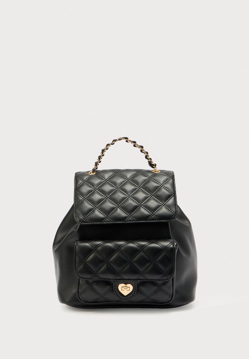 Sac à dos en cuir matelassé noir avec poche avant, fermoir cœur doré à fermeture à tourniquet et poignée tressée sur fond uni.