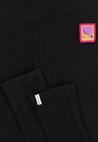 Zwarte geribbelde leggings met een roze en paarse "LOVE CLUB" patch en een witte "LOOXS" label aan de zoom. Zacht materiaal met een aansluitend ontwerp.