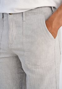 Ljust grå dogtooth-mönstrade byxor tillverkade av texturerat tyg, med sidofickor och rak skärning.