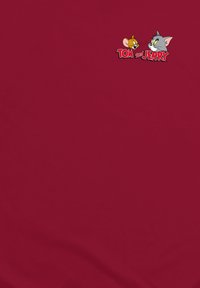 Maglietta rossa in cotone con un grafico ricamato di un topo giallo e un gatto grigio, con il testo "Tom e Jerry" in un carattere stilizzato.
