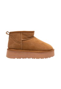 Bottine en suède beige avec un bout rond, un design bas et une semelle en caoutchouc texturé. Elle dispose d'une petite boucle à l'arrière pour un enfilage facile.