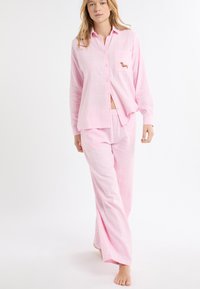 Set di pigiama a quadri rosa in tessuto morbido, con camicia abbottonata dotata di taschino sul petto e ricamo di un cane. Pantaloni larghi.
