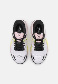 Białe i różowe buty sportowe z czarnymi akcentami, z czarnymi sznurówkami, perforowanymi noskami i neonowymi żółtymi detalami na podeszwach.