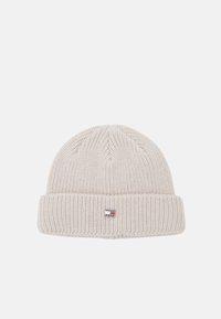 Gorro tipo beanie en punto beige claro. Presenta una textura acanalada y un puño plegado. Etiqueta de logo pequeña en la parte frontal.