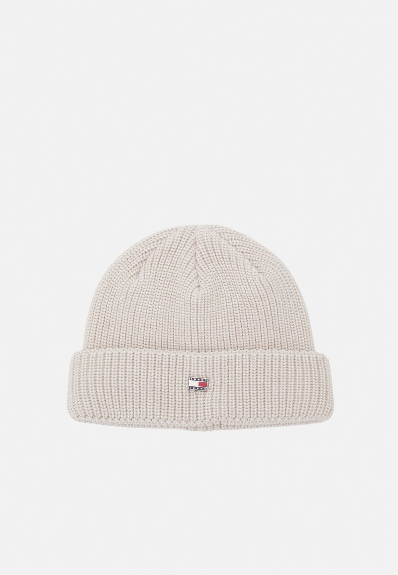 Gorro tipo beanie en punto beige claro. Presenta una textura acanalada y un puño plegado. Etiqueta de logo pequeña en la parte frontal.