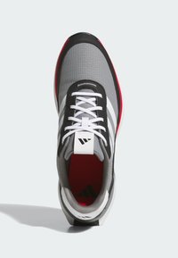 Szary but sportowy z siateczkową i syntetyczną cholewką, czarno-czerwonymi akcentami, białymi sznurowadłami oraz charakterystycznym logo na języku.