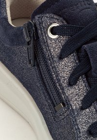 Marineblaue Sneakers mit einer strukturierten Oberseite, glitzerndem Finish, seitlichem Reißverschluss und kontrastierenden Schnürsenkeln auf einer weißen Sohle.