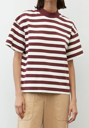 Persoon draagt een wit en bordeaux horizontal gestreept overhemd met korte mouwen, een bordeaux kraag en beige broek.