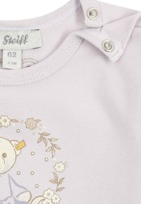 Lila Baumwollstrampler mit einem Bärenmotiv, umgeben von Blumen, Druckknöpfen an der Schulter und einem weichen, strukturierten Stoff.