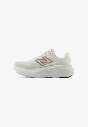 Valkoinen New Balancen juoksukenkä, jossa paksu pohja, verkkopäällinen, nauhakiinnitys ja vaaleanpunainen 'N'-logo sivussa.