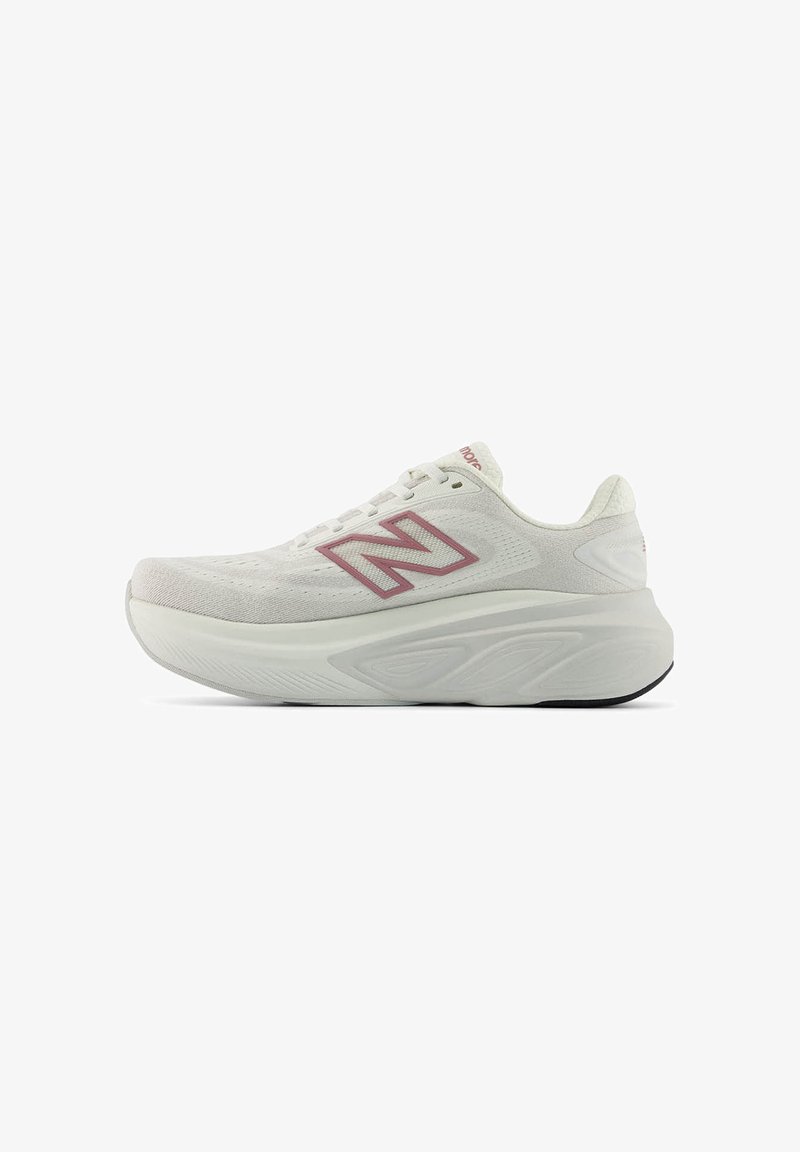 Λευκό αθλητικό παπούτσι New Balance με χοντρή σόλα, επάνω μέρος από δίχτυ, σχεδιασμό με κορδόνια και ροζ λογότυπο "N" στο πλάι.