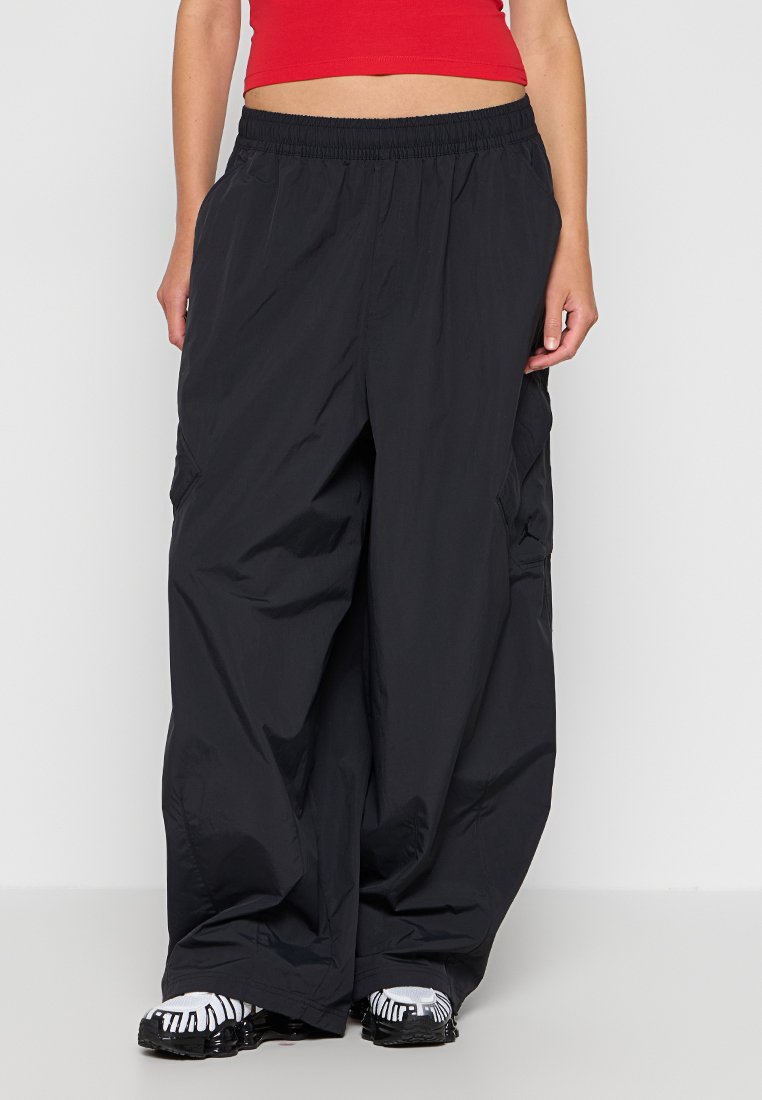 Pantaloni cargo neri, leggeri, con vita elastica, grandi tasche laterali e vestibilità ampia. Realizzati in materiale liscio e resistente all'acqua.