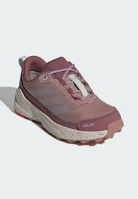 Lila und graue Trailrunningschuhe mit einer strukturierten Oberseite, ausgestattet mit einer verstärkten Zehenkappe und einer gesprenkelten weißen Zwischensohle mit einer profilierten Außensohle.