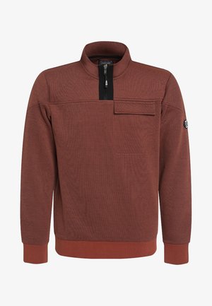 Pull couleur rouille avec demi-fermeture éclair, col montant, poche poitrine à rabat, poignets et ourlet côtelés, et écusson logo circulaire sur la manche gauche.