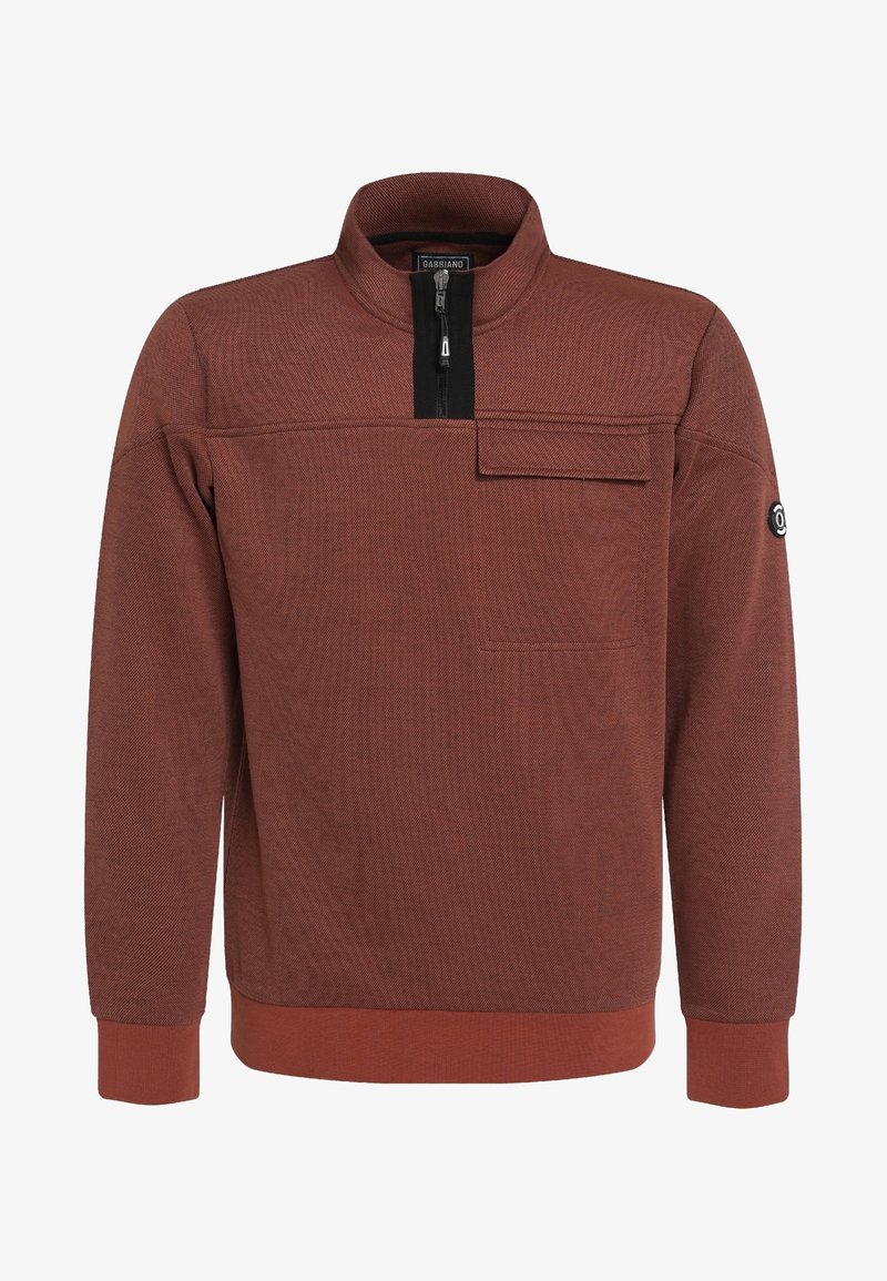 Pull couleur rouille avec demi-fermeture éclair, col montant, poche poitrine à rabat, poignets et ourlet côtelés, et écusson logo circulaire sur la manche gauche.