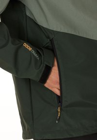 Waterproof jacket with a two-tone design. The top is light gray, the bottom is dark green, features a zippered pocket and adjustable cuffs.