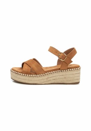 Sandalias de cuña de ante en tono tostado con un diseño de tiras cruzadas, correa ajustable en el tobillo y plataforma de yute trenzado. Textura suave y acabado delicado.