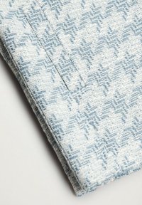 Tkanina w kolorach niebieskim i białym, z wzorem pepitki. Miękka tekstura z widocznym przeszyciem i złożonym brzegiem.