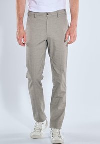 Light gray, textured trousers with a slim fit, featuring a zip fly and button closure. Paired with white sneakers for a casual look.