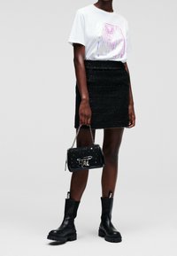 White t-shirt with colorful graphic design, black sparkly mini skirt, black ankle boots with chunky soles, and a small black handbag.