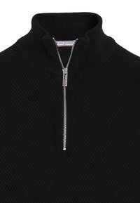 Sort strikket pullover med høj krave, kvartlynlås foran og tekstureret mønster. Har sølvlynlås og mærke-detaljer ved halsudskæringen.