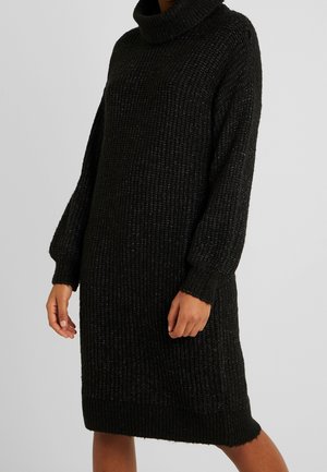 Robe en tricot noir avec un col roulé haut, des manches longues et une coupe décontractée. Le tissu texturé présente des fils métalliques subtils.