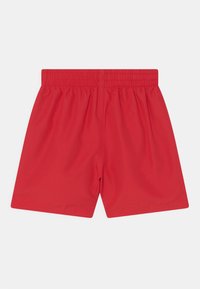 Shorts de sport rouges avec une taille élastique, texture lisse et coupe droite. Pas de poches visibles ni d'éléments de design supplémentaires.
