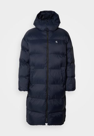 Marineblå pufferjakke med hette, med hel lengde glidelås foran, quiltet design og en liten logo på brystet. To frontlommer.