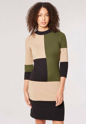 Sukienka dzianinowa z wzorem w bloki kolorów w odcieniach beżowym, oliwkowozielonym i czarnym. Rękawy ¾ oraz okrągły dekolt. Gładka tekstura.