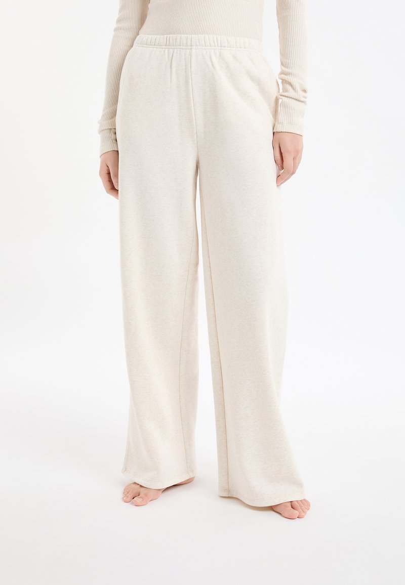 Beżowe, szerokie spodnie do noszenia na co dzień wykonane z miękkiego materiału z elastycznym pasem. Gładka tekstura z minimalnymi detalami przeszyć.