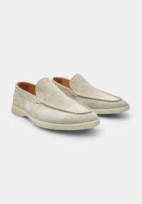 Pantofi slip-on din suede de un bej deschis, cu detalii cusute și talpă din cauciuc. Prezintă o textură netedă și un design cu vârful rotund.