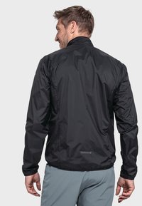 Schwarze, leichte Jacke mit hohem Kragen, elastischen Bündchen und einem reflektierenden Akzent auf dem Rücken, entworfen für Outdoor-Aktivitäten.