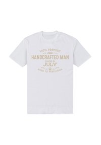 Camiseta de algodón blanca con mangas cortas que presenta texto en beige claro que dice "100% PREMIUM HECHO A MANO HECHO EN JULIO ENVEJECIDO A LA PERFECCIÓN."