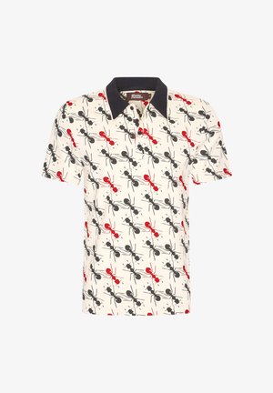 Lyhythihainen polo-paita kermanvärisestä kankaasta, jossa on mustia ja punaisia abstrakteja kuvioita, klassinen kaulus ja kolmen napin lista.