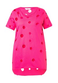 T-shirt rosa a maniche corte con molteplici fori circolari, realizzato in tessuto morbido, con scollatura rotonda e un orlo posteriore leggermente più lungo.