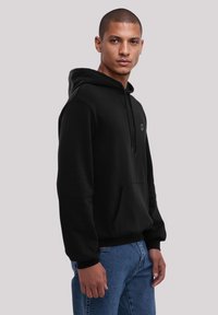 Black hoodie made of cotton-blend fabric, featuring a front pouch pocket, adjustable drawstring hood, and a small logo on the chest.